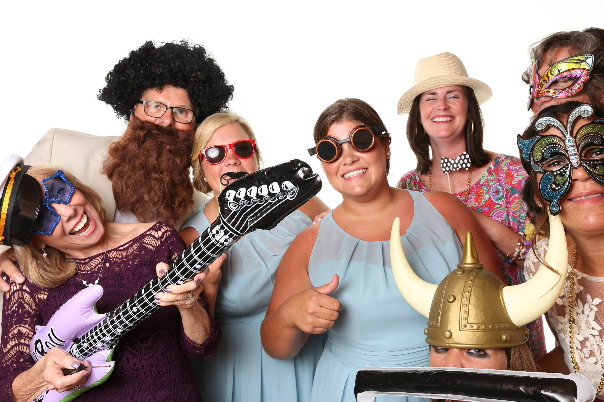 Guest at wedding in Asheville, NC using Forge Mountain Photography's photo booth. Guest are psing on a completely white background with no shadows. They are using all sorts of props like viking helmets, fake beards, wigs, and musical instruments.
