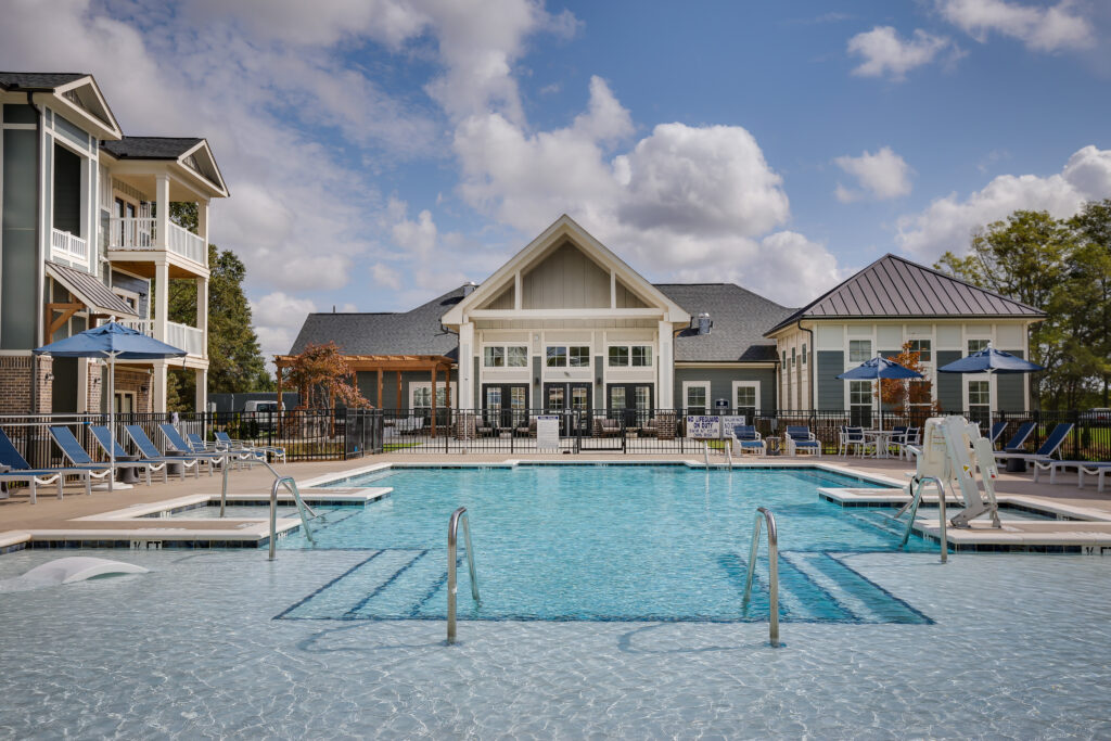 View from the back of the Saltwater pool looking at the clubhouse. The water is glimmering and the pool appears to be very shallow. Simpsonville, SC commercial photographer