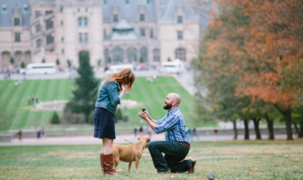 Close up of Eser proposing with Biltmore house partially in view