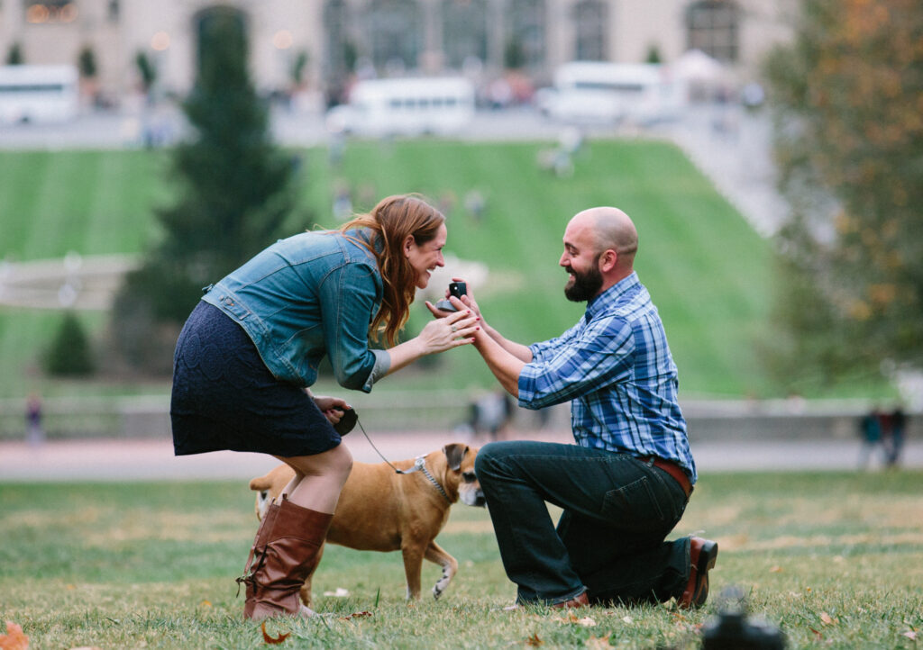 Eileen + Eser Proposal photography – Eser down on one knee proposing, Eileen is clearly happy and smiling.