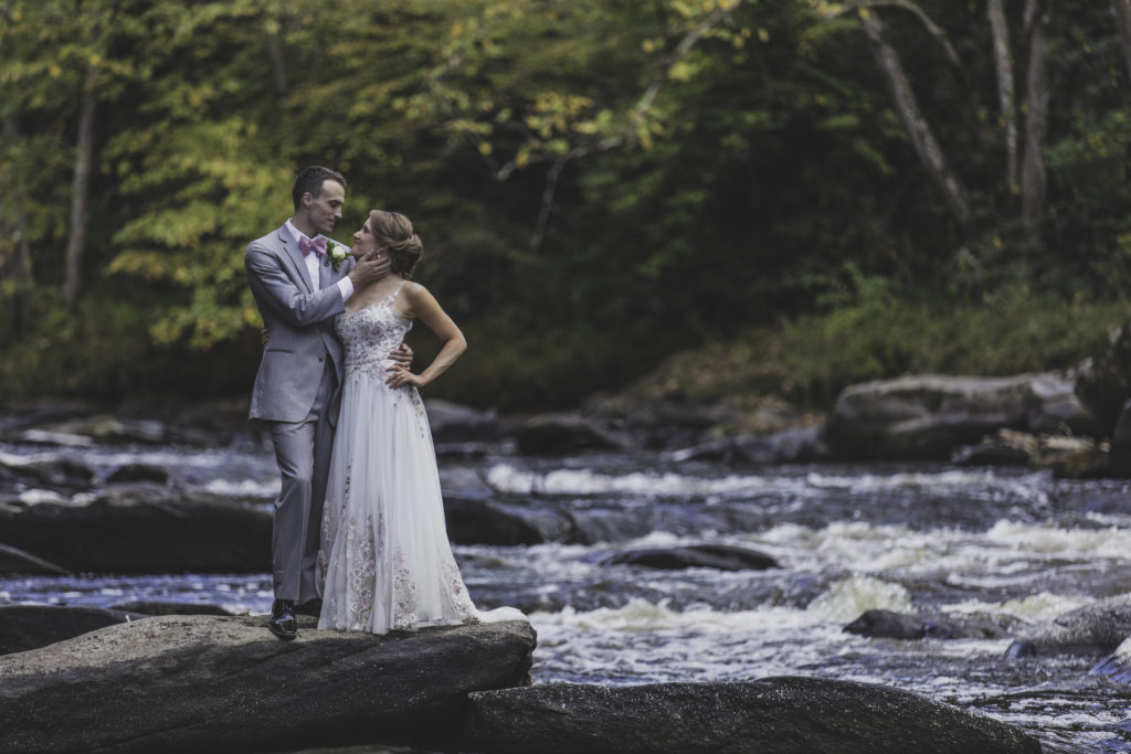 Elopement Photographer taking pictures in front of rushing water in Dupont State Forest as the recently married couple stand on a rock