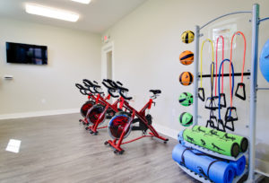 A professional property photoshoot is the photo of the cycling room in the fitness center there are red bikes and the background and a variety of workout balls in the foreground.