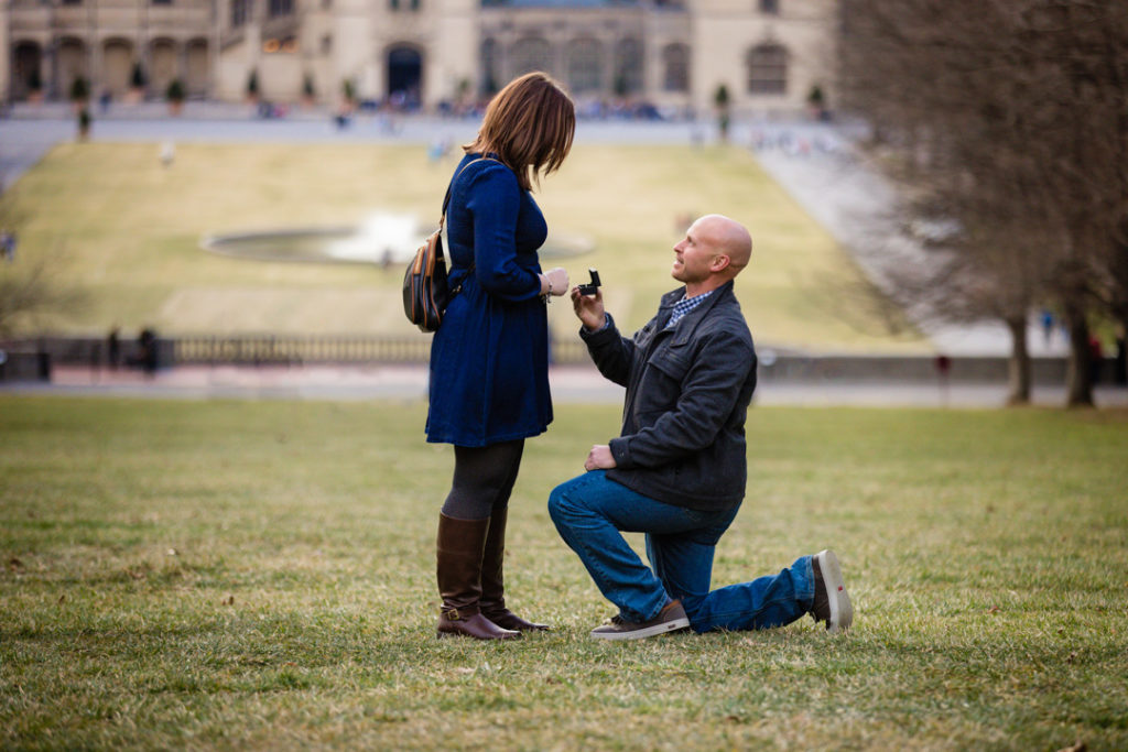 Eric brings out the ring box for his surprise proposal while down on one knee.