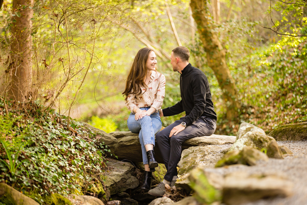 Couple sitting on rock over a stream, Real Engagement Biltmore Estate