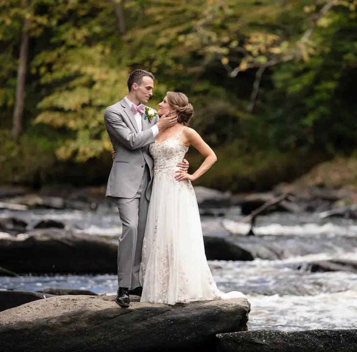 Couple standing on rocks in a river during their elopement near Asheville