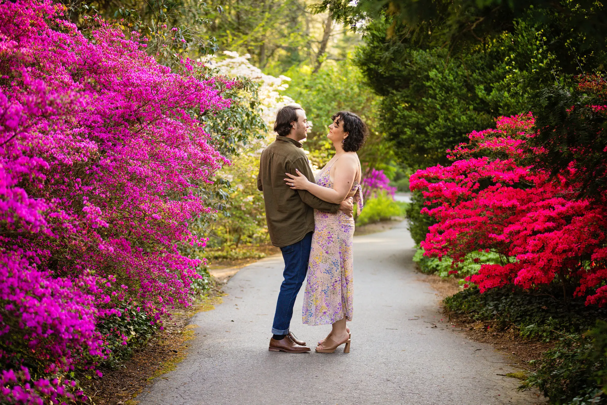Couple dancing on a garden path with azaleas in full vivid bloom during a Biltmore engagement session