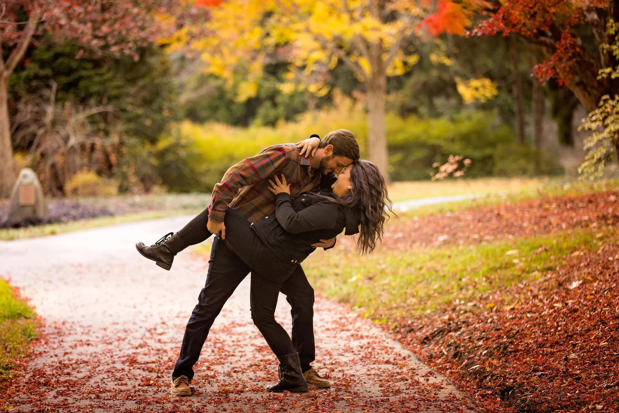 Couple doing a dance dip beneath a red maple with yellow fall color behind them at Biltmore