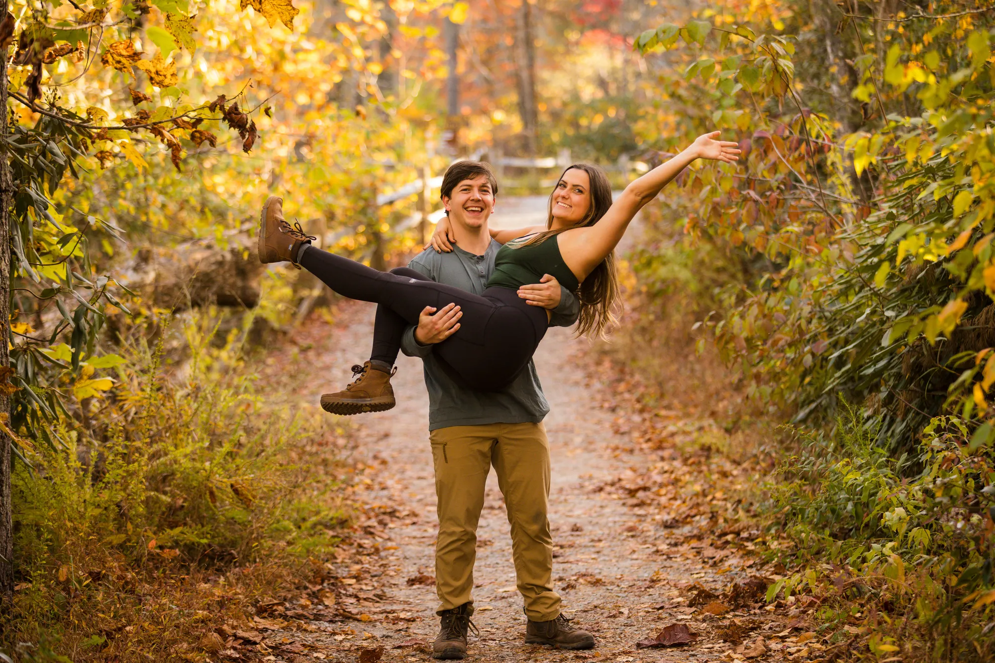 Adventure engagement photos on a leaf-covered trail, DuPont NC