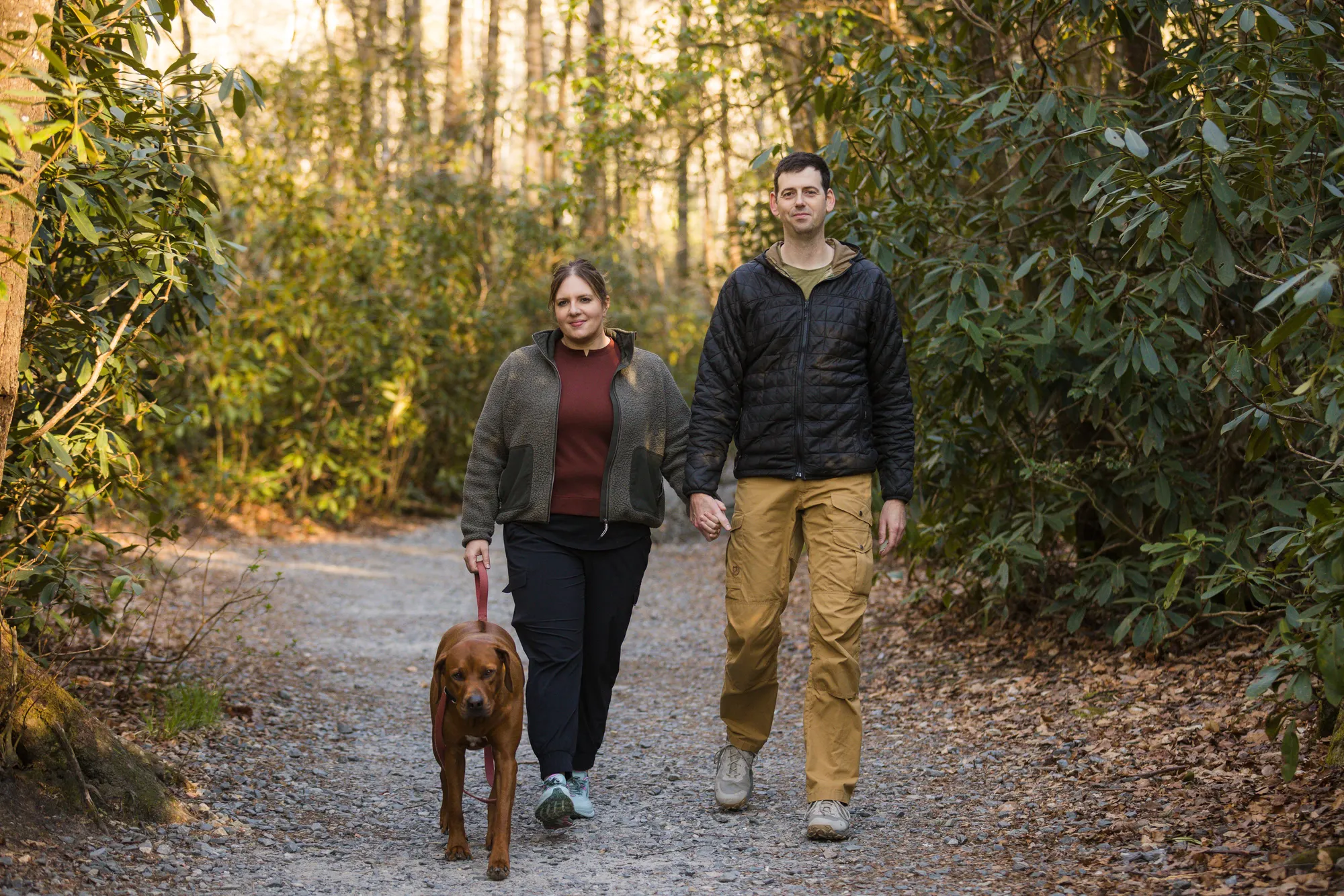 Couple hiking the Triple Falls Trail with their leashed dog, DuPont