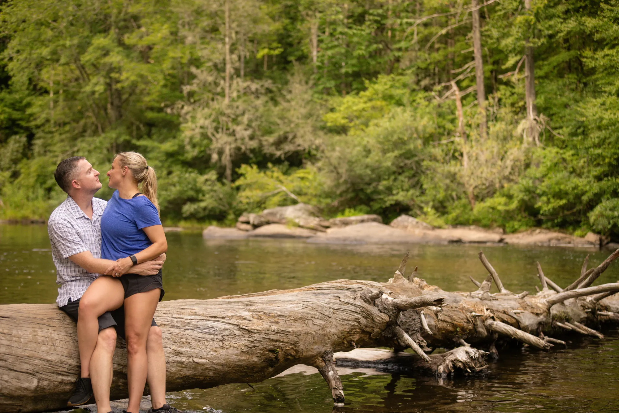 Couple sitting on a fallen log over the Little River, DuPont State Forest
