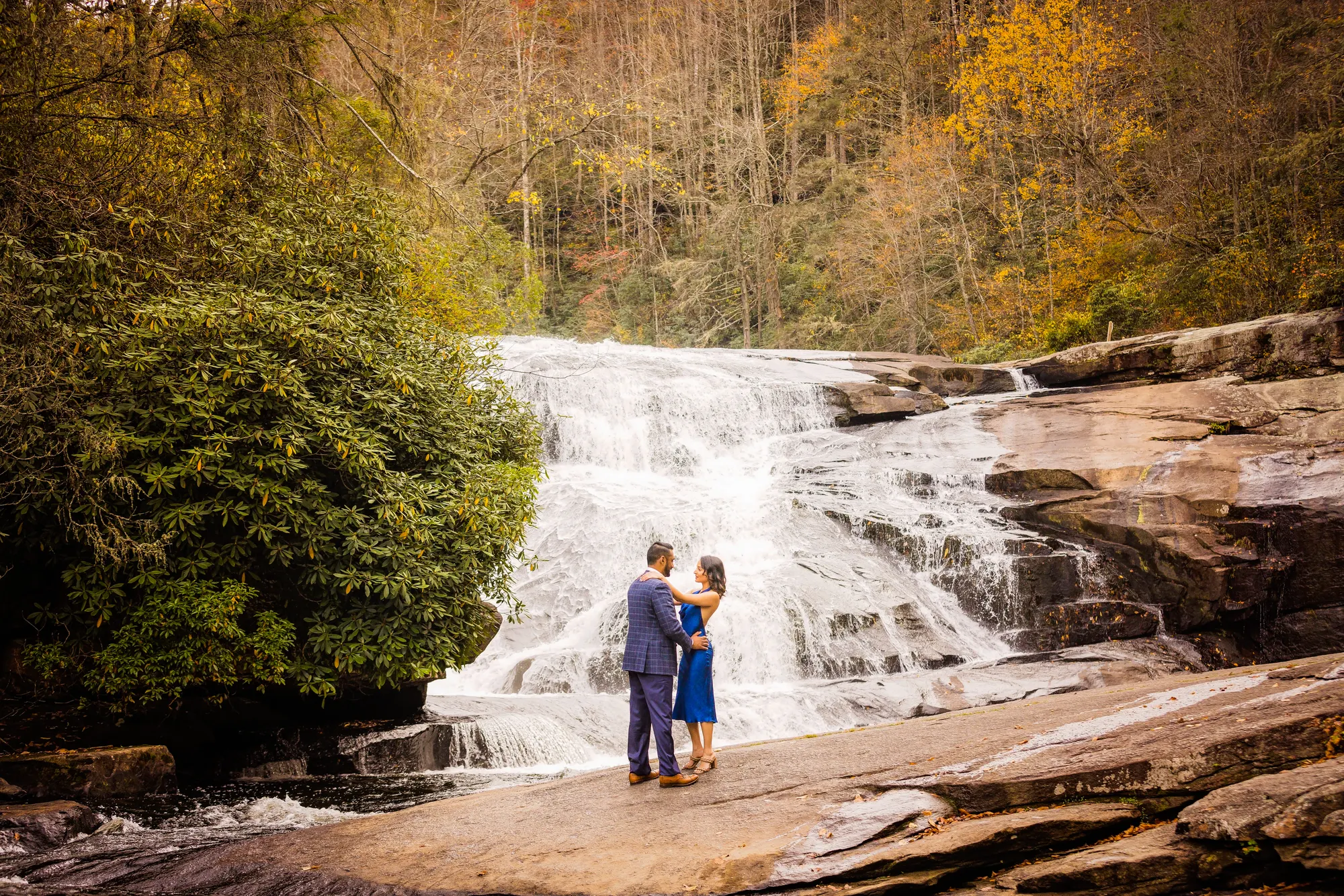 Fall engagement photos at Triple Falls near Brevard NC, gold canopy behind the couple