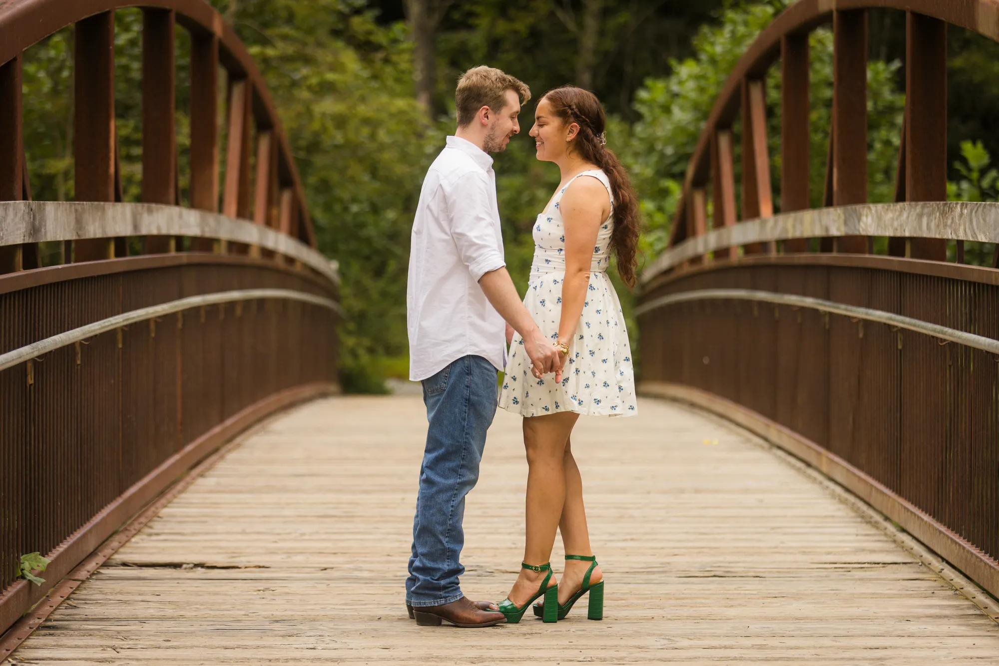Holding hands on the arched footbridge, DuPont State Forest engagement session