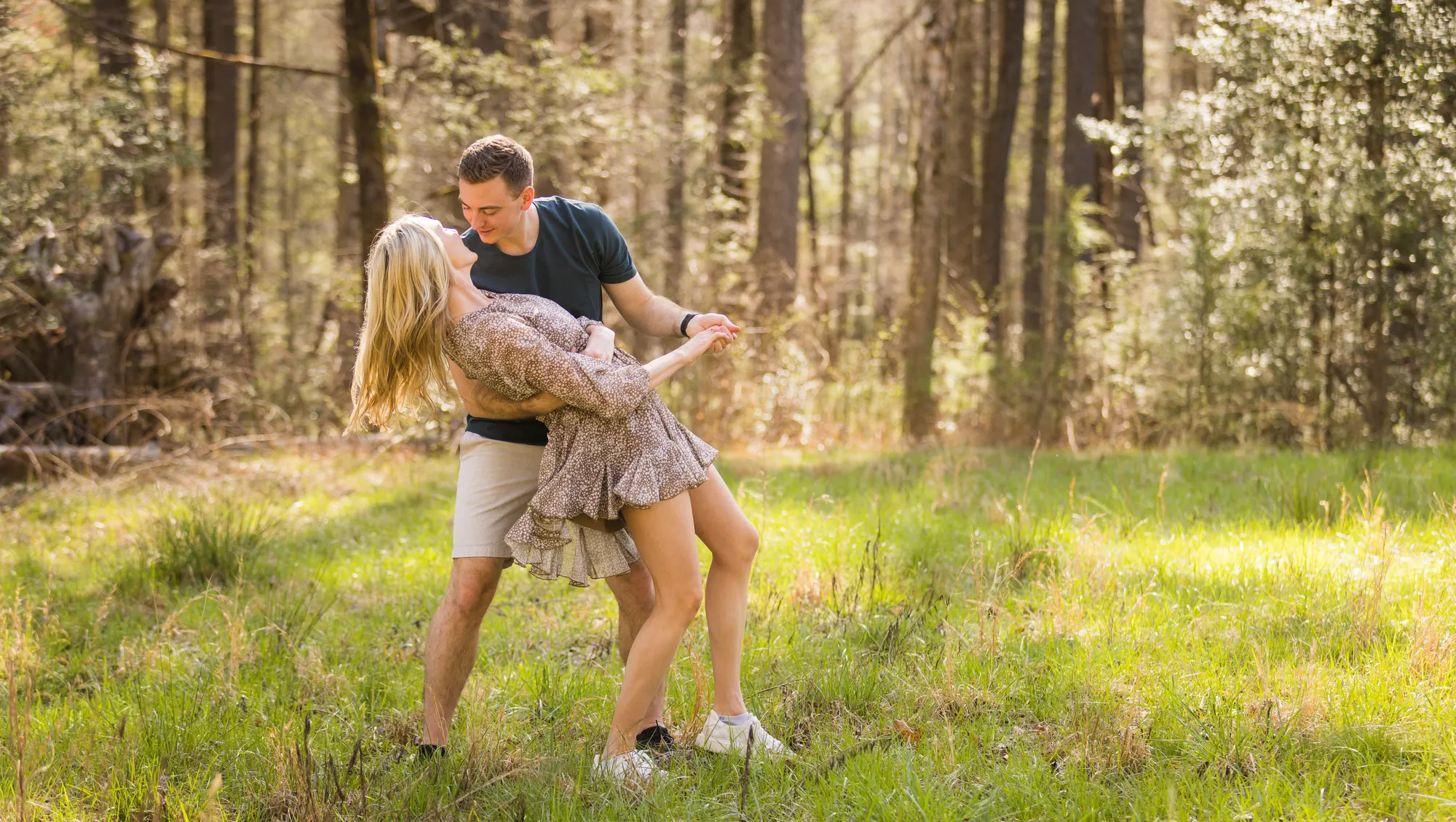 Dip kiss in a sunlit forest meadow, DuPont NC engagement photos