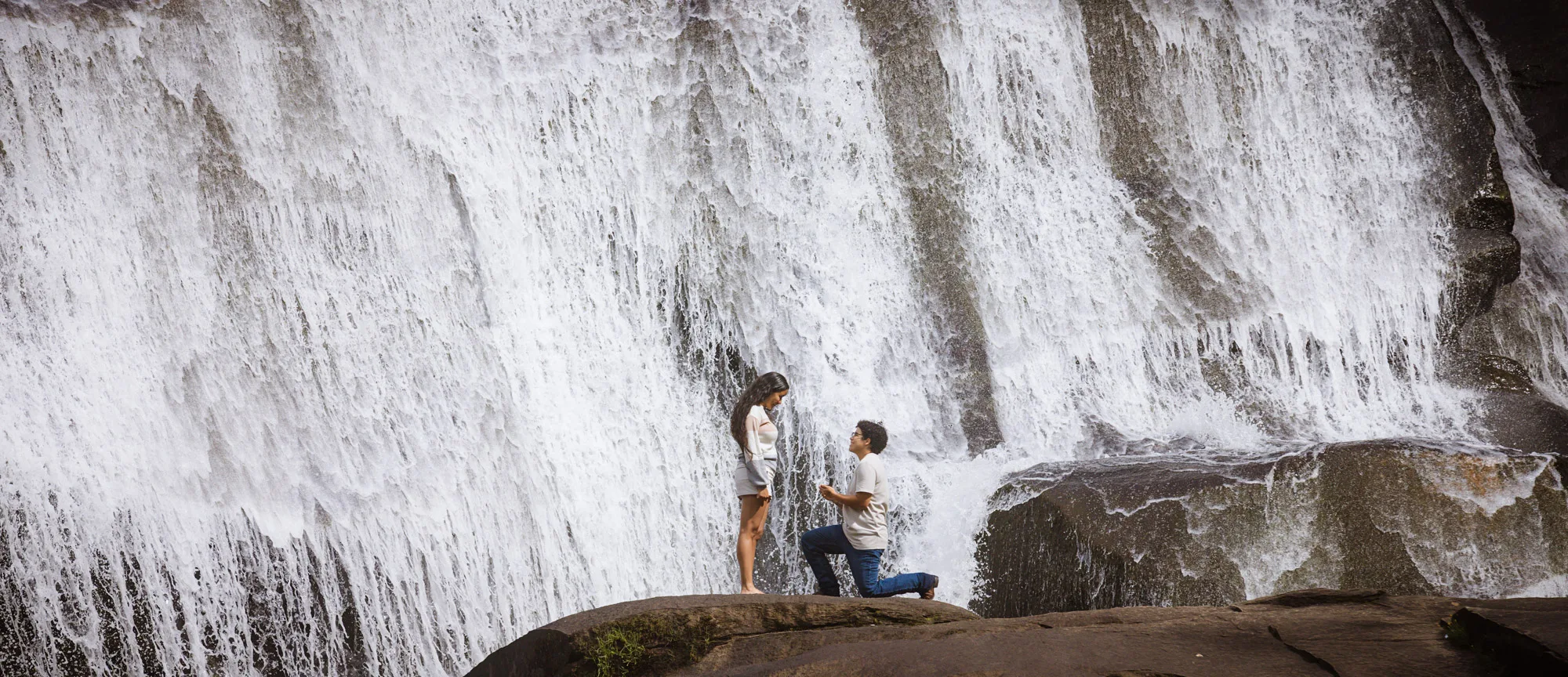 Surprise proposal at the base of High Falls in DuPont State Forest, one knee in front of the 150-foot cascade