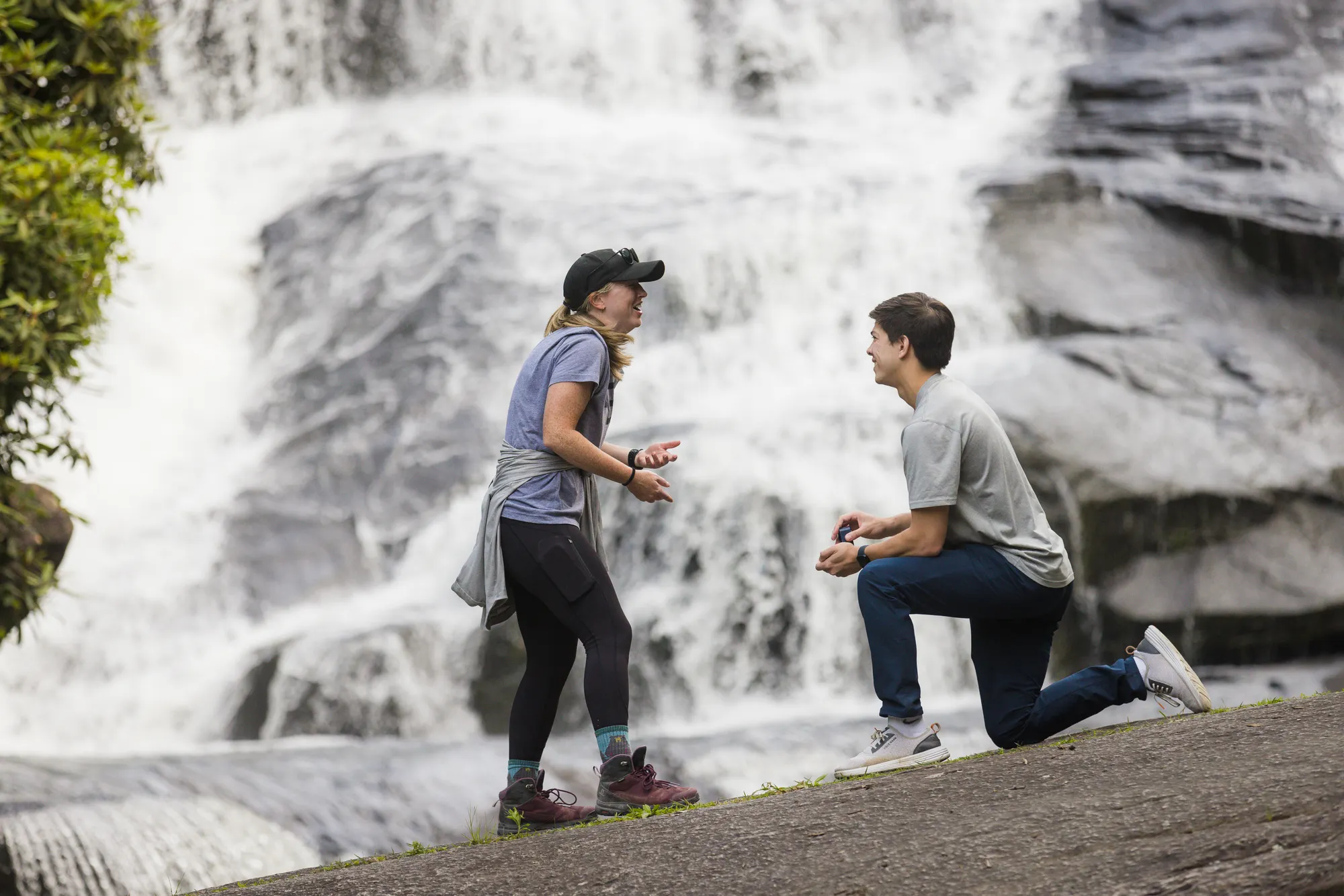 Hiker proposing on one knee at Triple Falls, DuPont State Forest