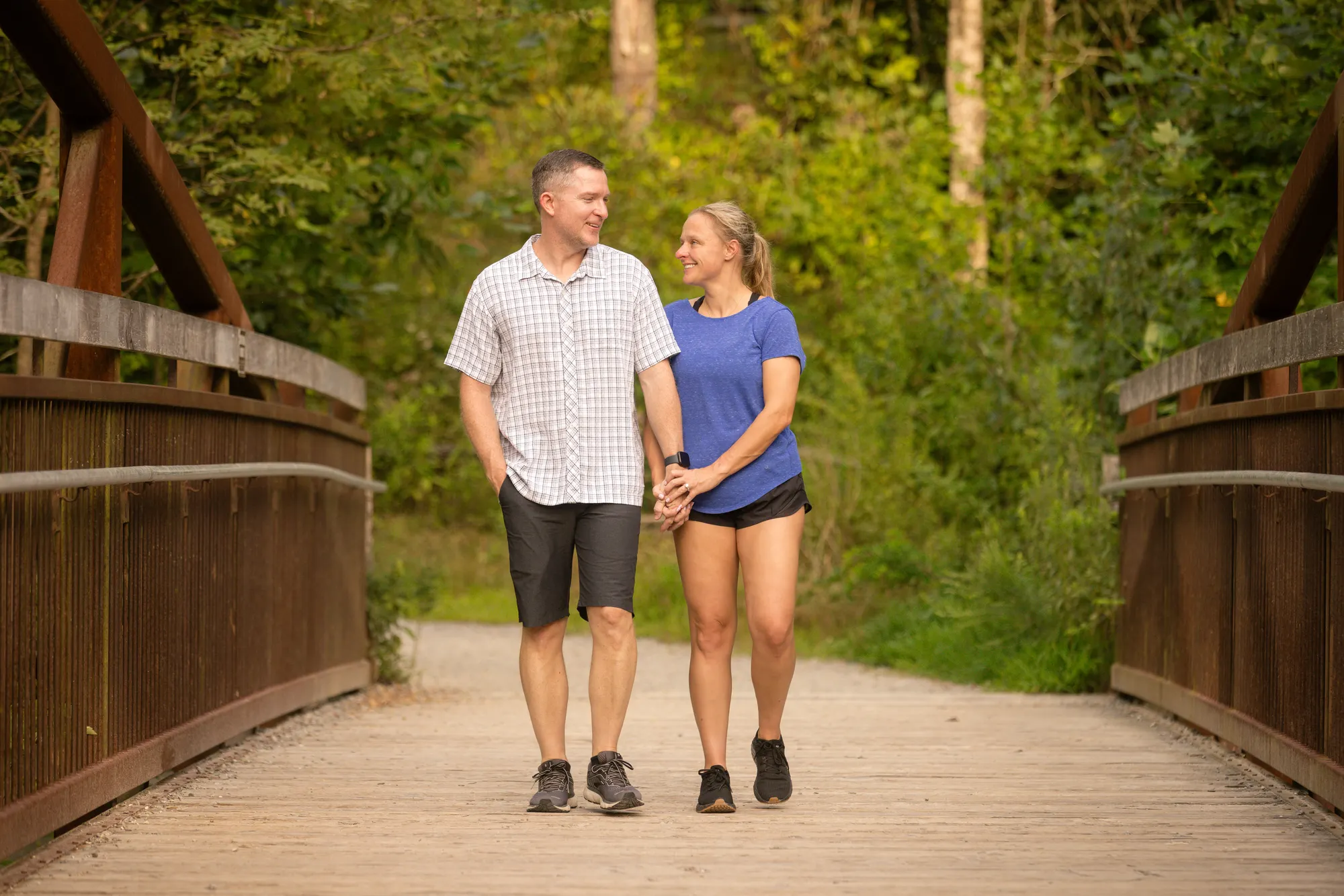 Couple walking across the metal footbridge on the Triple Falls Trail in DuPont State Forest