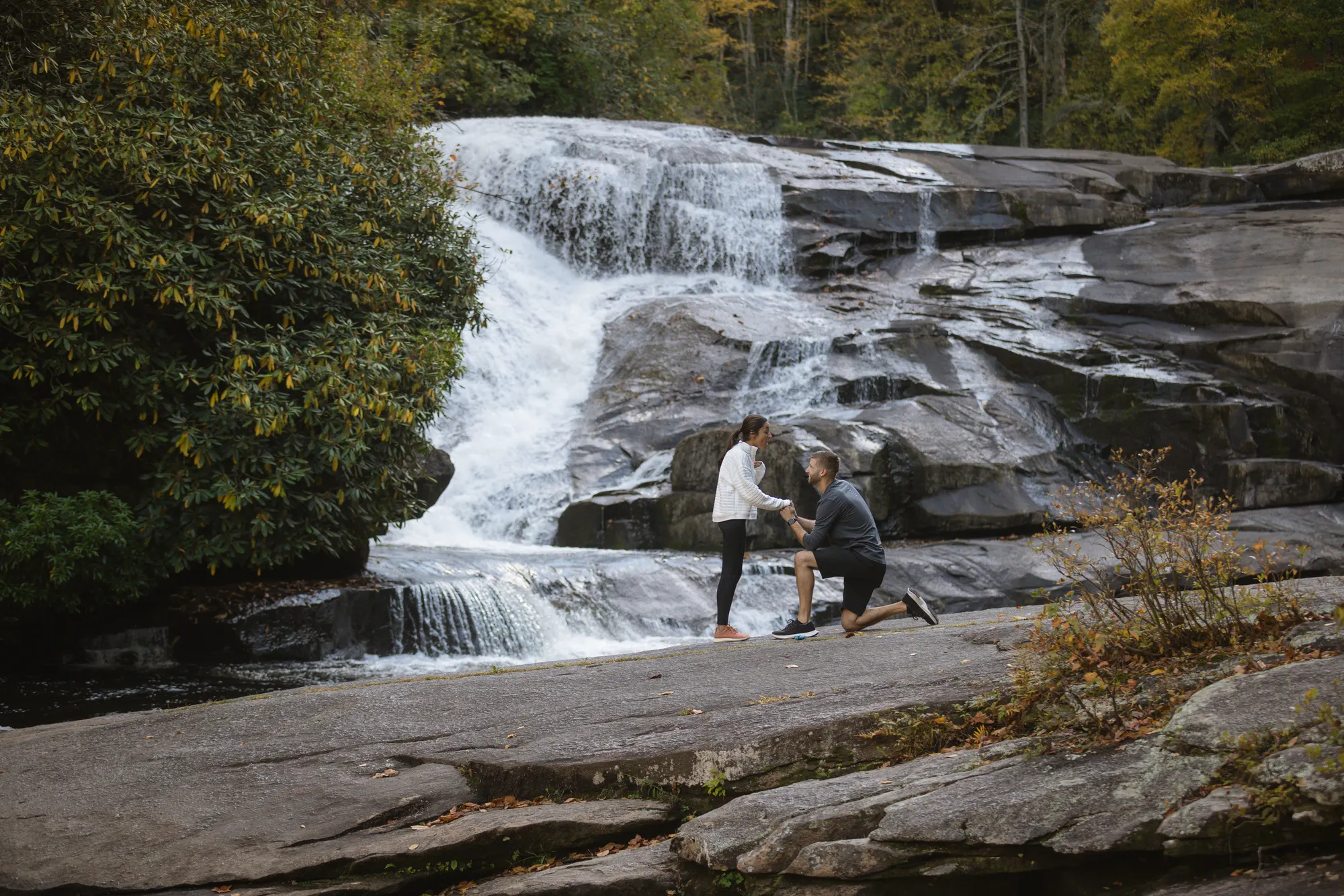 Surprise proposal on one knee at the lower cascade of Triple Falls, DuPont State Forest, peak fall color
