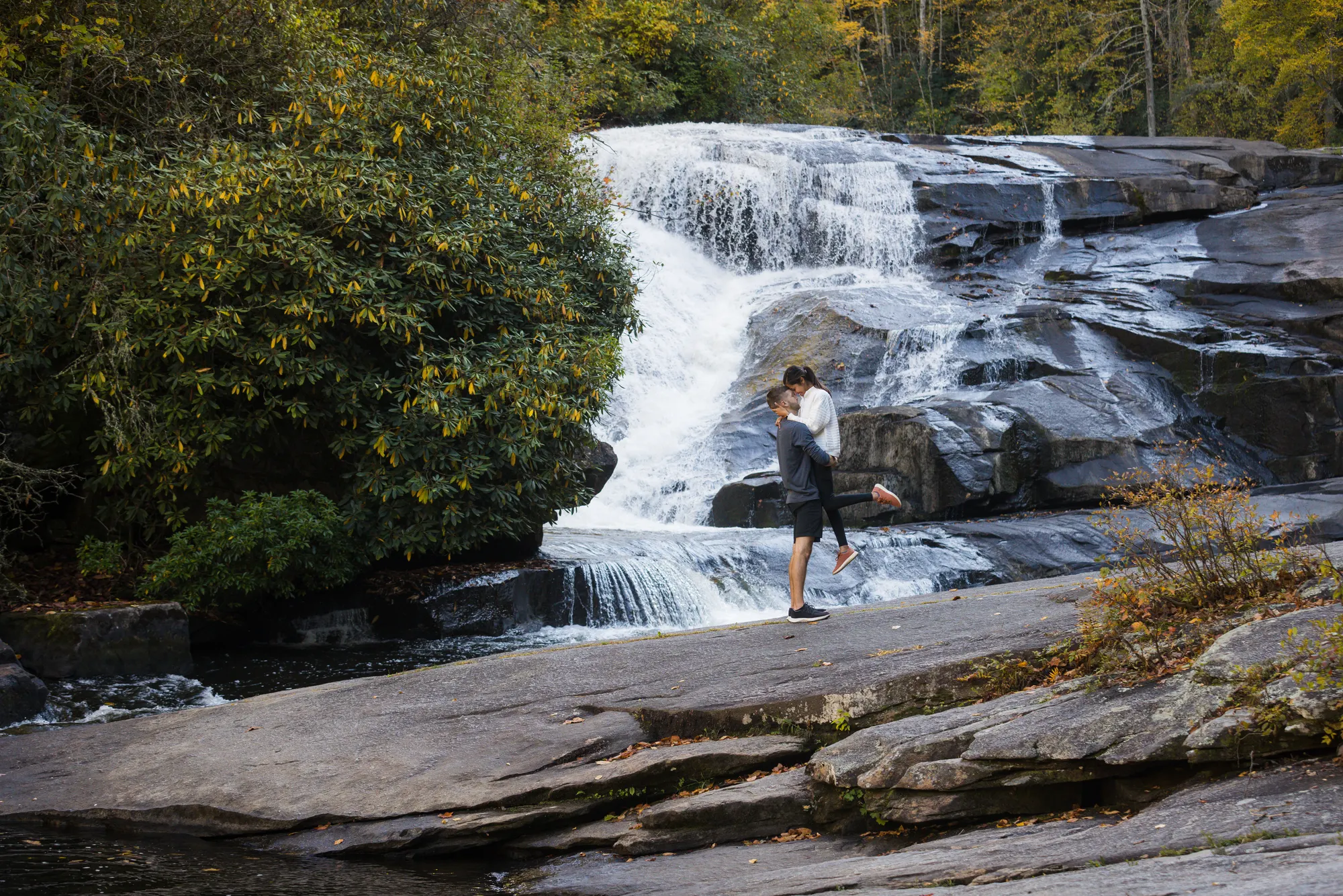 Playful engagement photos at Triple Falls in fall, western North Carolina