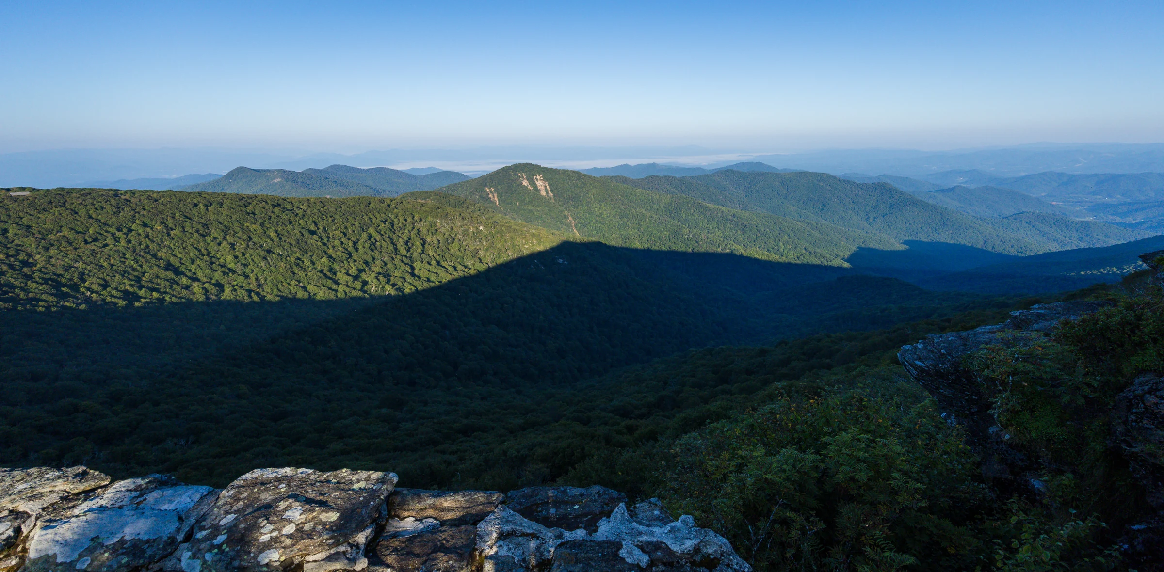A forested valley below Craggy Pinnacle under a clearing sky