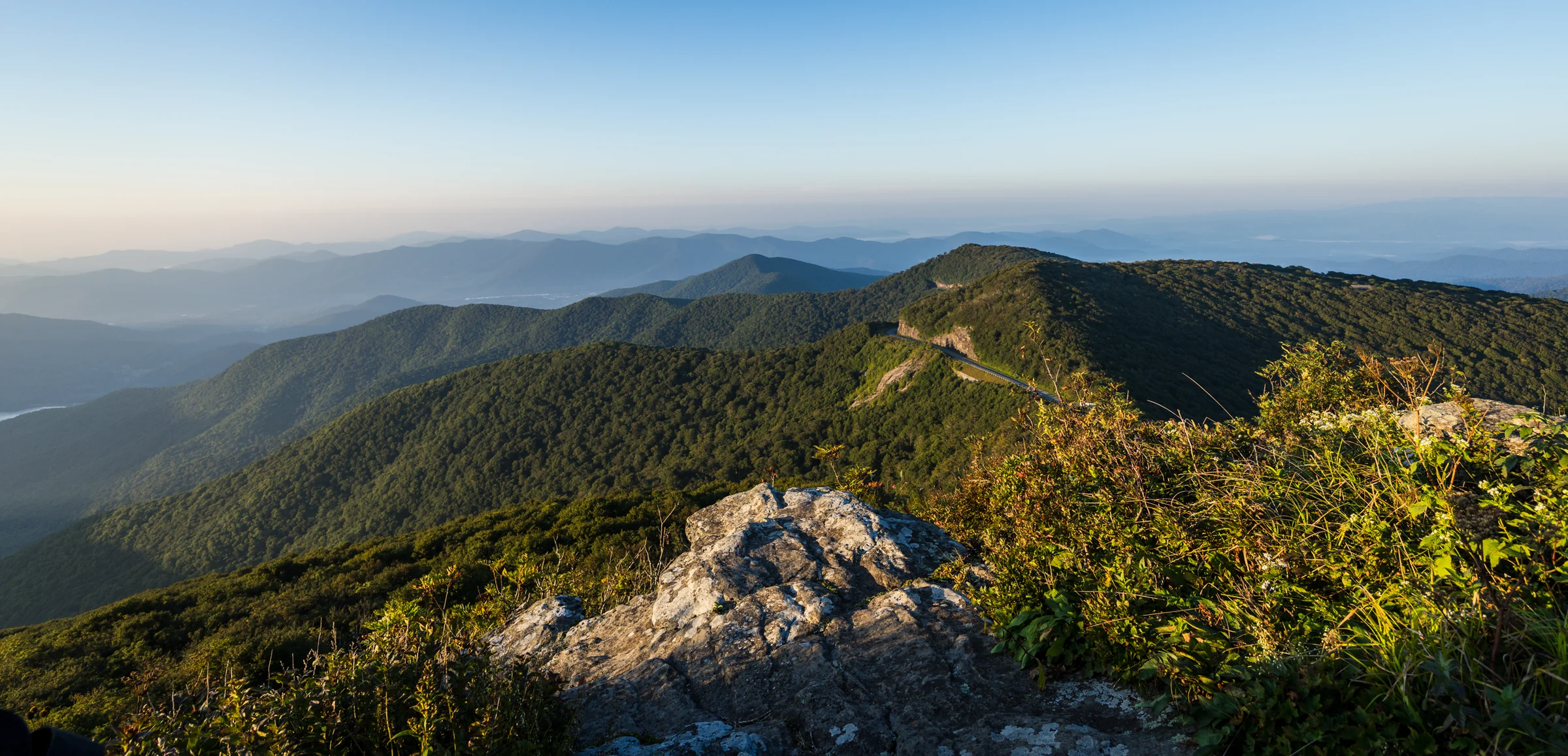 Weathered rock in the foreground and layered Blue Ridge mountains beyond, seen from Craggy Pinnacle