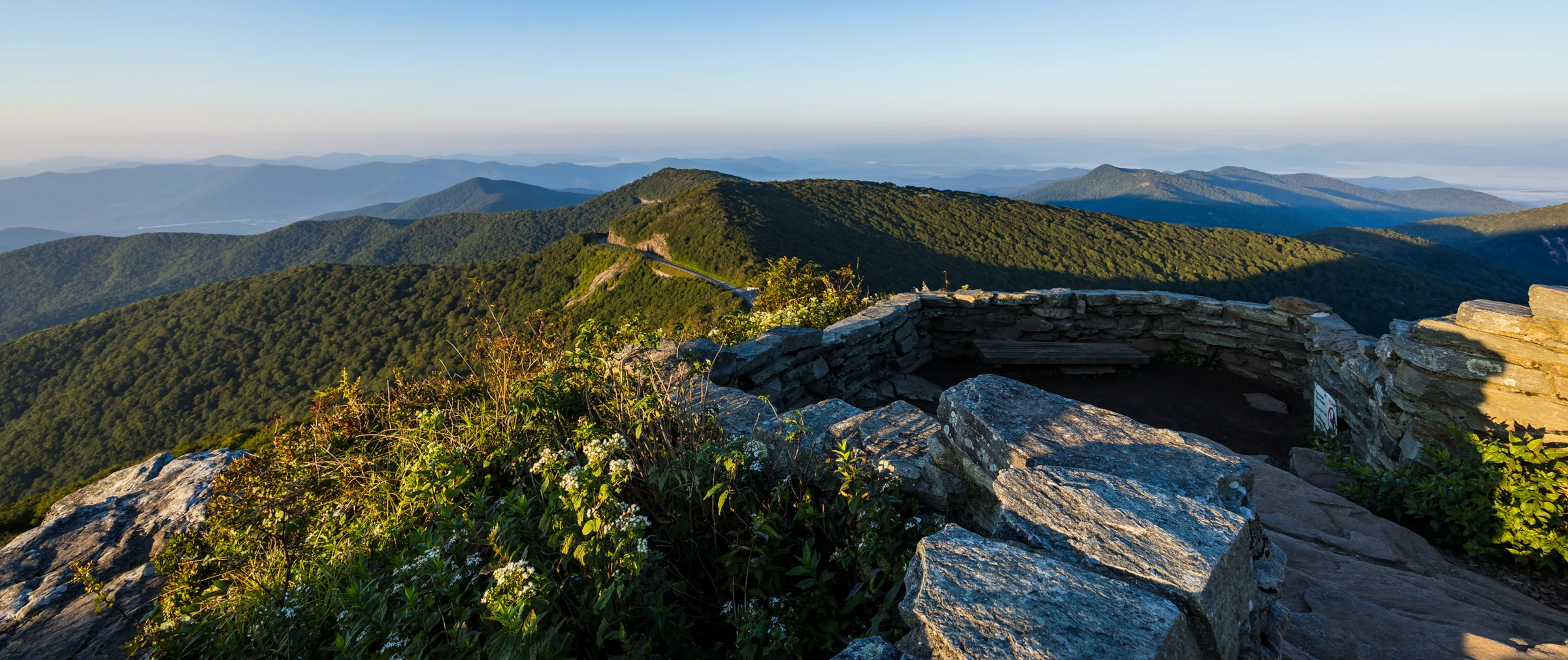 The low stone wall of the summit overlook on Craggy Pinnacle with layered Blue Ridge mountains in the distance