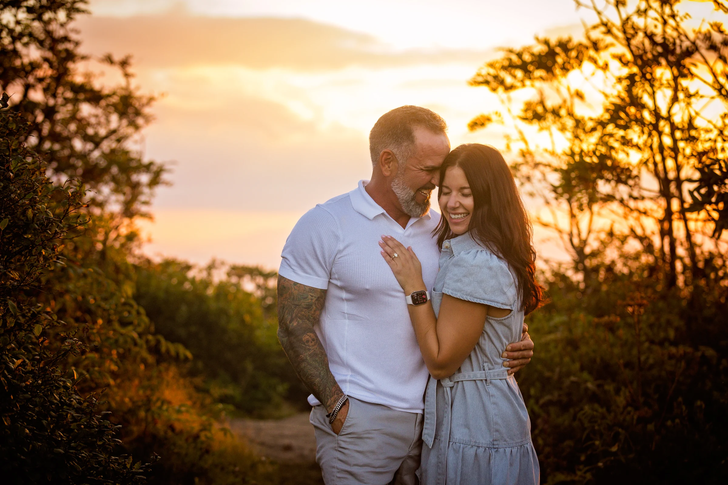Scott and Jaci close together at golden hour on Craggy Pinnacle with the Blue Ridge Mountains behind them