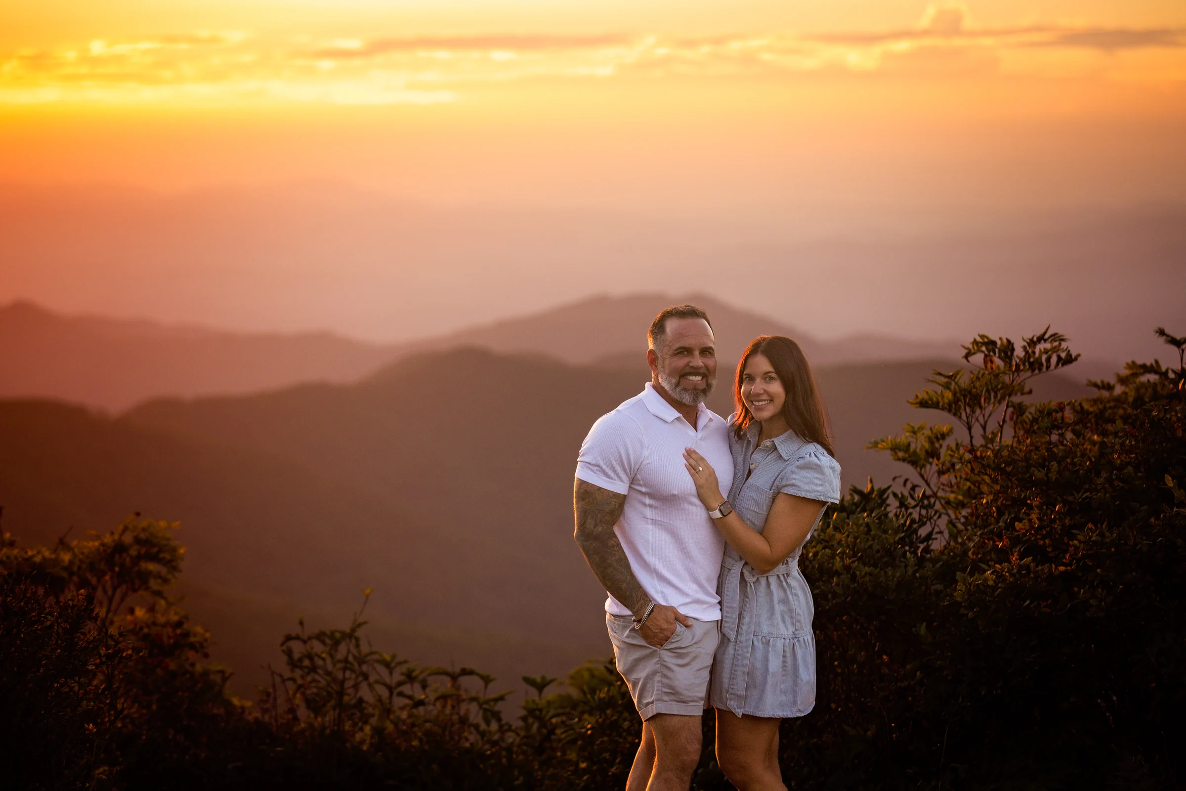Scott and Jaci beneath a deep orange sunset sky above the Blue Ridge Mountains on Craggy Pinnacle