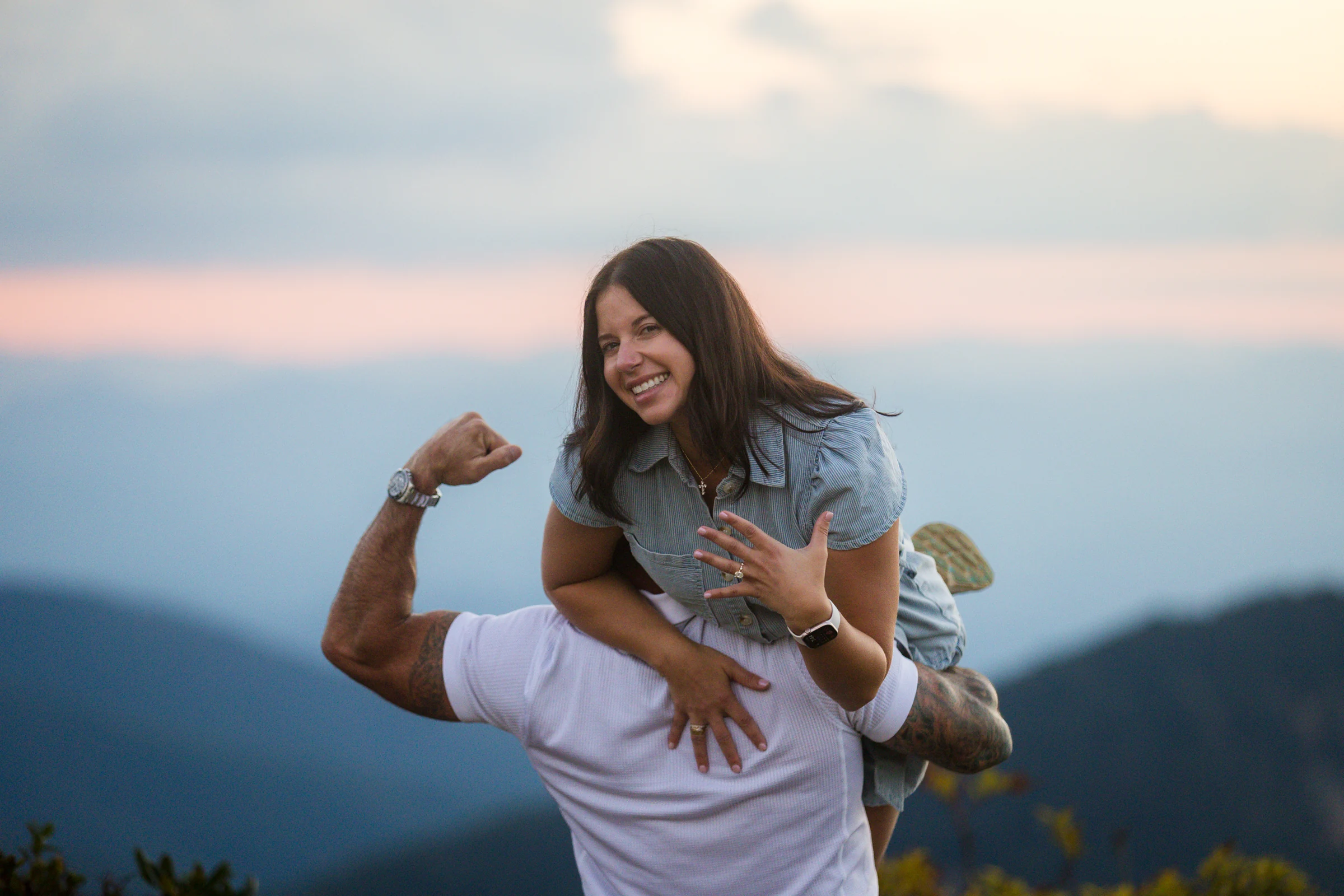 Scott and Jaci playful and relaxed after the proposal on Craggy Pinnacle, golden evening light and mountains behind them