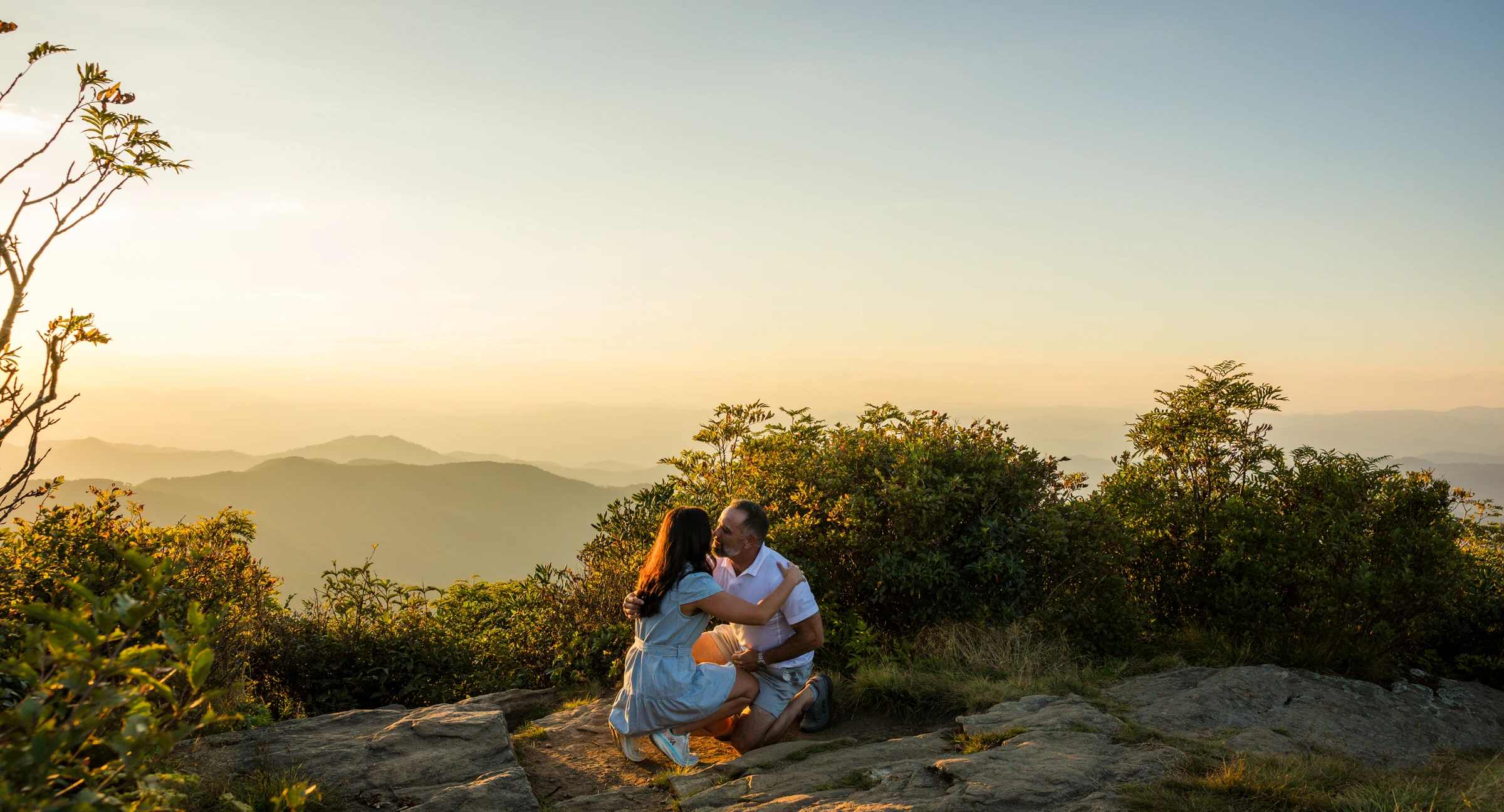 Scott and Jaci embrace after the proposal with the Blue Ridge mountains behind them