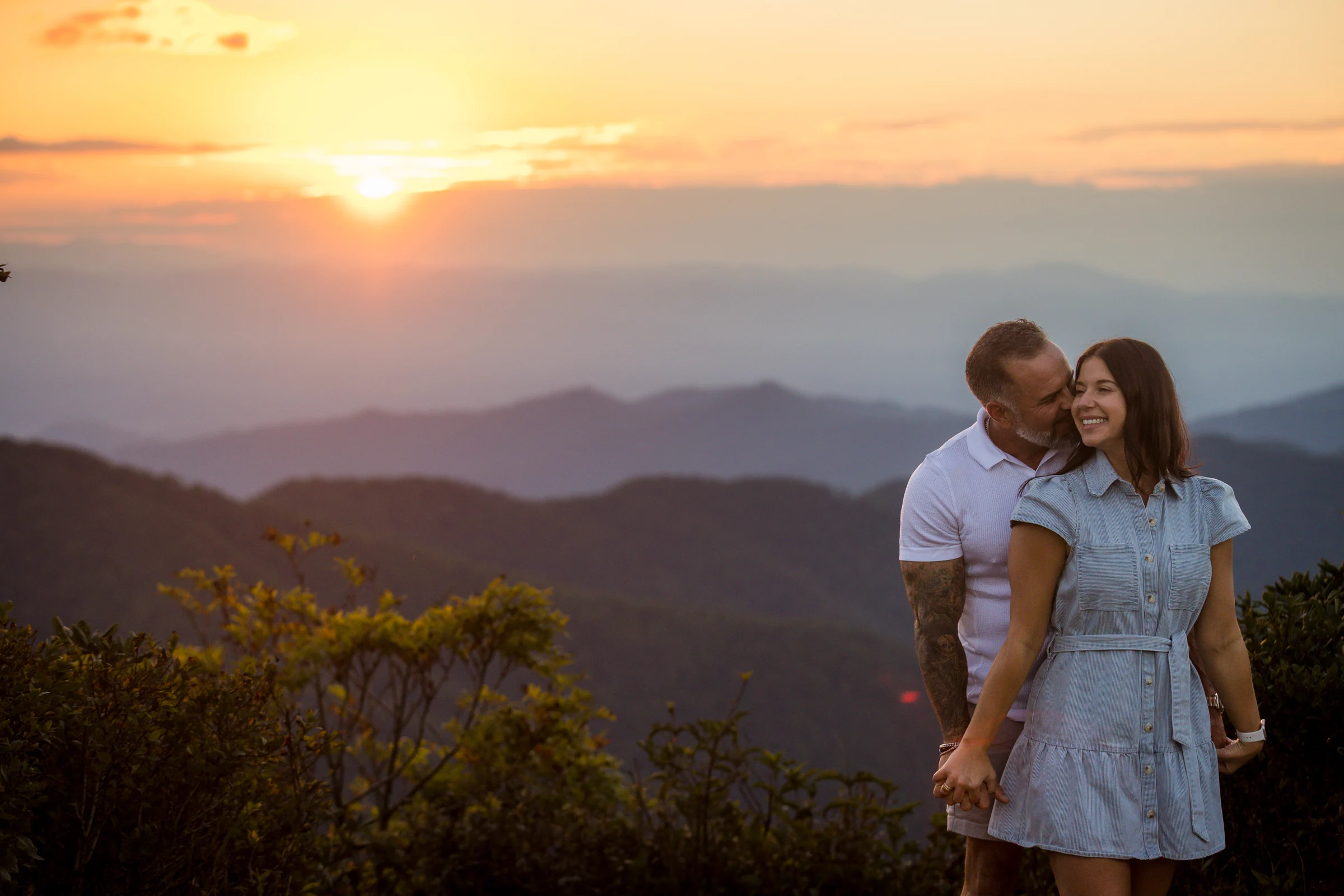 Scott kisses Jaci on the cheek at sunset on the west ledge of Craggy Pinnacle, Blue Ridge Parkway