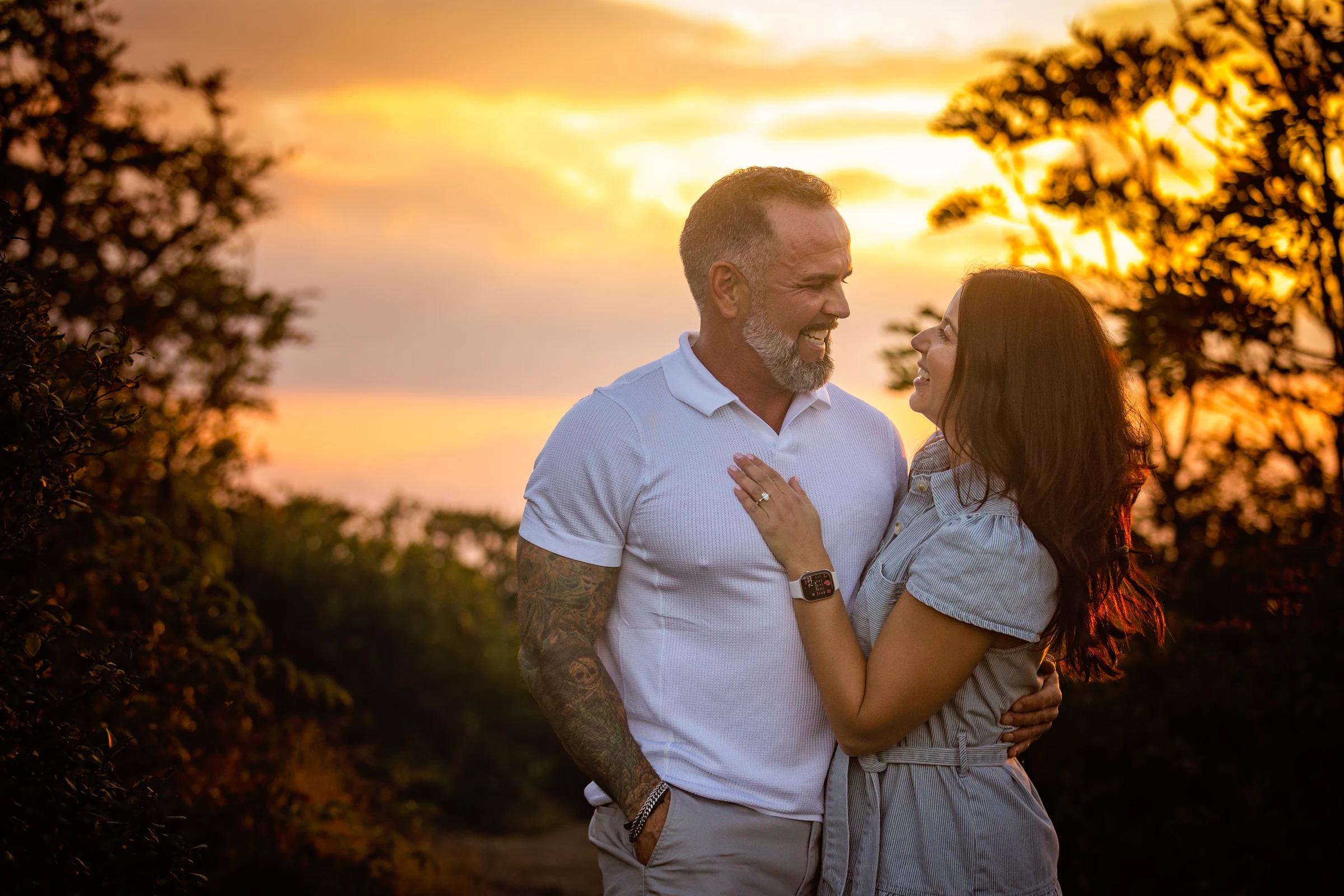 Scott and Jaci laughing at sunset on Craggy Pinnacle with mountain ridges behind them